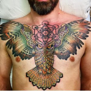 Large, colorful chest piece tattoo with geometric metatrons cube and owl totem with open wings in black and color ink by Natan Alexander