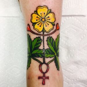 Tattoo of female power symbols with yellow flower and green leaves in color ink by K Lenore Siner